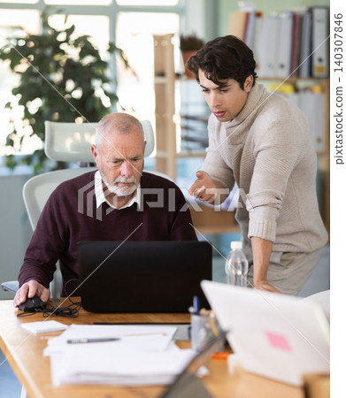 Guy helps elderly man complete task on laptop Guy helps elderly man complete task on laptop 140307846
