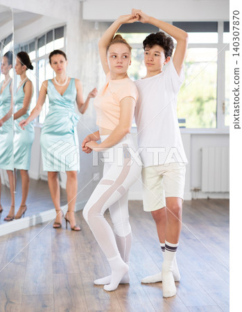 Experienced dance teacher teaching ballroom dancing to a of teenagers in studio 140307870