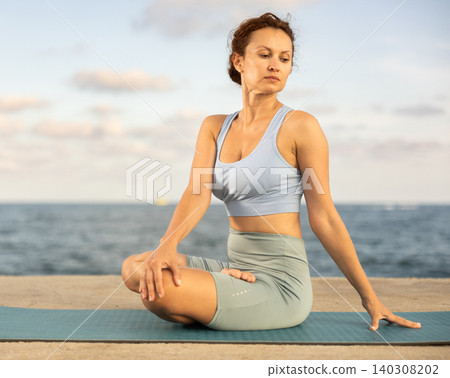 Woman performing Ardha Matsyendrasana position yoga training Woman performing Ardha Matsyendrasana position yoga training 140308202