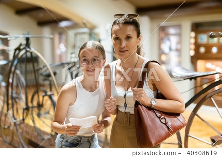 Mom and teenage daughter are looking at antique bicycle 140308619