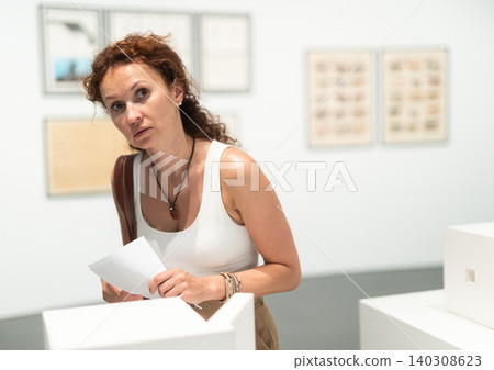 Middle-aged woman looking at building models in museum Middle-aged woman looking at building models in museum 140308623
