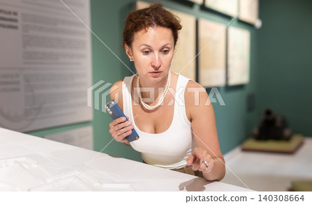 Middle-aged woman looking at building models in museum Middle-aged woman looking at building models in museum 140308664