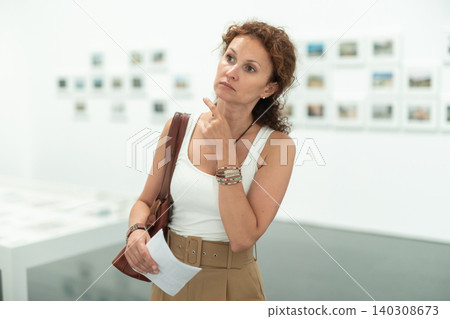 Woman observing photographs on display in photo gallery Woman observing photographs on display in photo gallery 140308673