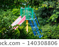 A colorful park slide surrounded by green trees 140308806