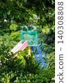 A colorful park slide surrounded by green trees 140308808