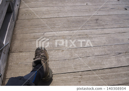Footwear for hikers walking along a wooden boardwalk 140308934