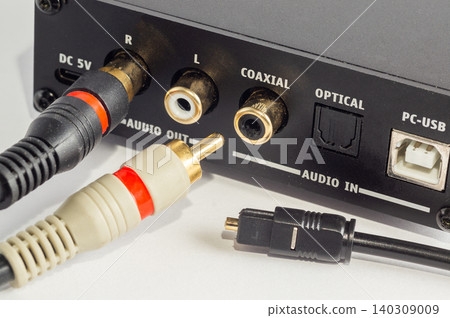 Close-up of RCA connectors plugged into an audio device and an optical cable. 140309009