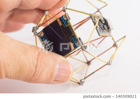 A close-up of a handmade decorative clock held in a hand. A close-up of a handmade decorative clock held in a hand. 140309021