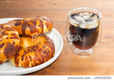 Close-up cheese bagel and Coca-Cola with ice in wood background Close-up cheese bagel and Coca-Cola with ice in wood background 140309364