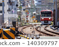 The lowered level crossing barrier and the blurred red train in the background. 140309797