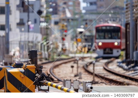 降低的平交道欄桿和背景中模糊的紅色列車。 140309797