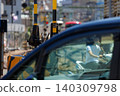 A view of a railway crossing barrier and a train in an urban area from inside a car. 140309798