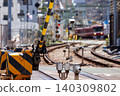 A railway crossing barrier and a blurred red train in the background. 140309802