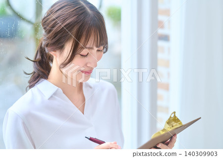 Portrait of a young woman writing on a clipboard Portrait of a young woman writing on a clipboard 140309903