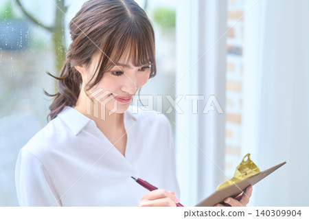 一位微笑的女士正在認真填寫文件。 140309904