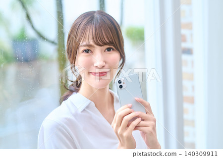 Portrait of a woman smiling while holding a smartphone 140309911