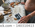 Pregnant woman baking cookies, announcing baby coming soon 140310413