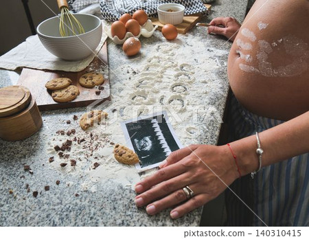 Pregnant woman baking cookies with ultrasound and flour Pregnant woman baking cookies with ultrasound and flour 140310415