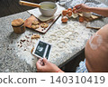 Pregnant woman showing ultrasound while baking cookies 140310419