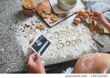 Pregnant woman announcing baby with ultrasound and baking ingredients Pregnant woman announcing baby with ultrasound and baking ingredients 140310420