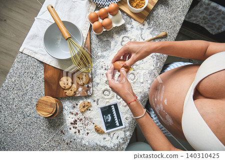 Pregnant woman baking cookies with ultrasound and flour Pregnant woman baking cookies with ultrasound and flour 140310425