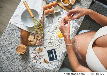 Pregnant woman baking cookies revealing ultrasound baby Pregnant woman baking cookies revealing ultrasound baby 140310427
