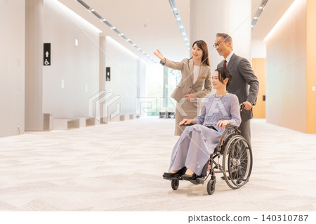 工作人員正在協助一位坐在輪椅上的女士 工作人員正在協助一位坐在輪椅上的女士 140310787