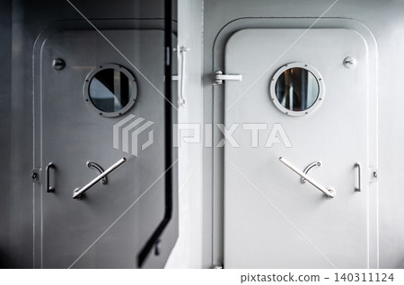Heavy metal door with round porthole window and lever handle reflected in the mirror Heavy metal door with round porthole window and lever handle reflected in the mirror 140311124