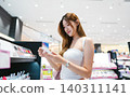 Gen z woman shopping for cosmetics in a modern beauty store choosing makeup trend products on shelf 140311141