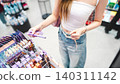 Gen z woman shopping for cosmetics in a modern beauty store choosing makeup trend products on shelf 140311142