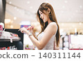 Gen z woman shopping for cosmetics in a modern beauty store choosing makeup trend products on shelf 140311144