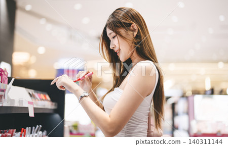 Gen z woman shopping for cosmetics in a modern beauty store choosing makeup trend products on shelf Gen z woman shopping for cosmetics in a modern beauty store choosing makeup trend products on shelf 140311144