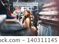 Young adult woman gen Z shopping choosing used clothing second hand shop fast fashion lifestyles 140311145