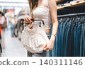 Young adult woman gen Z shopping choosing used clothing second hand shop fast fashion lifestyles 140311146