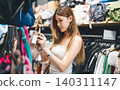 Young adult woman gen Z shopping choosing used purse bags second hand shop fast fashion lifestyles 140311147