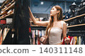 Young adult woman gen Z shopping choosing used clothing second hand shop fast fashion lifestyles 140311148