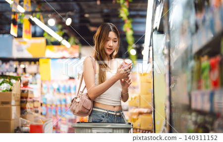 Young adult asian woman consumer choosing beverage drink at asia supermarket store choice buying Young adult asian woman consumer choosing beverage drink at asia supermarket store choice buying 140311152