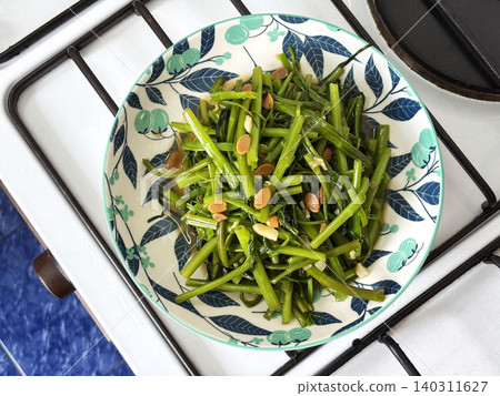 Easy homemade Thai stir-fried water spinach. Healthy, quick morning glory dish with garlic on a floral plate 140311627