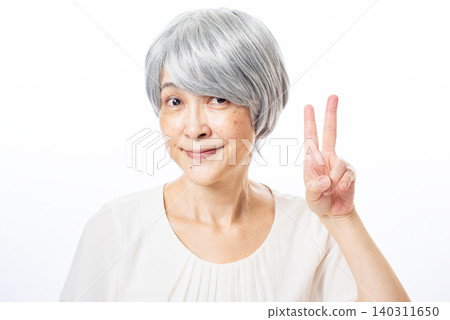 一位白髮蒼蒼的老婦人面帶微笑，比出和平手勢。 140311650