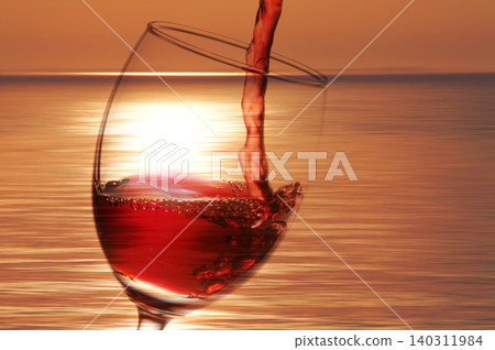 Red wine poured into a glass reflecting the evening scenery Red wine poured into a glass reflecting the evening scenery 140311984