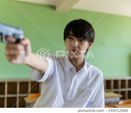 A young man holding a gun in a classroom. A young man holding a gun in a classroom. 140312068