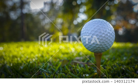 Golf ball on tee in the evening golf course with sunshine background. Golf ball on tee with blue sky background. Golf ball on tee in the evening golf course with sunshine background. Golf ball on tee with blue sky background. 140312174