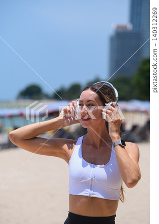 Healthy lifestyle concept: Happy woman listening to music on the sunny beach 140312269