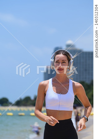 Portrait of a fit woman running on the beach wearing wireless headphones Portrait of a fit woman running on the beach wearing wireless headphones 140312304
