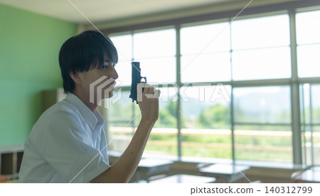 A boy holding a gun in a classroom 140312799