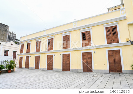 Yellow facade of the historic St Lazarus Church Parish House with brown wooden shutters and cobblestone courtyard Yellow facade of the historic St Lazarus Church Parish House with brown wooden shutters and cobblestone courtyard 140312955
