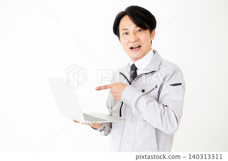 A middle-aged businessman in gray work clothes looks surprised to see a laptop computer in a white background. 140313311