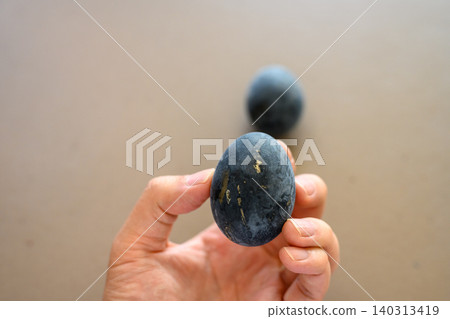 Hand holding a black egg: Delicious Hand holding a black egg: Delicious 140313419