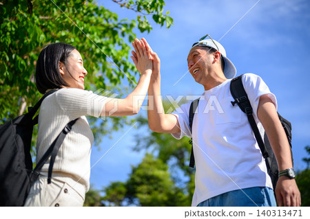 A man and woman high-five each other outdoors. A man and woman high-five each other outdoors. 140313471