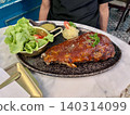 Close up view of delicious grilled pork ribs with sauce and salad on a restaurant table. 140314099